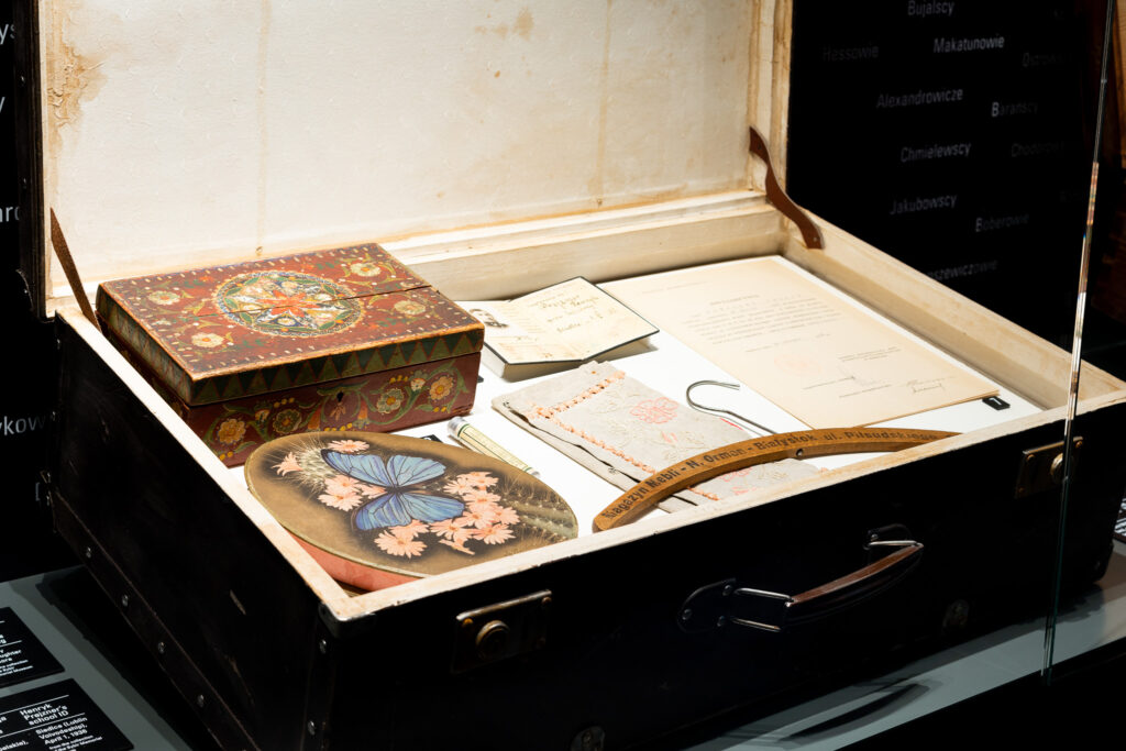 Zdjęcie przedstawia eksponat otwartej walizki z dokumentami oraz przedmiotami.