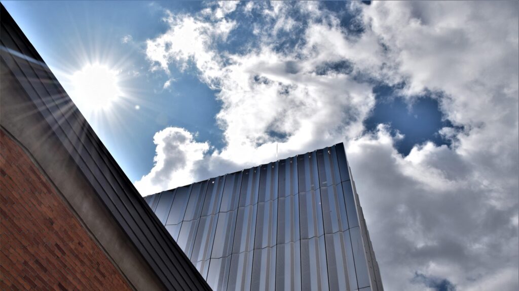 Zdjęcie przedstawia rzut ściany elewacyjnej budynku Muzeum z widokiem na zachmurzone niebo.