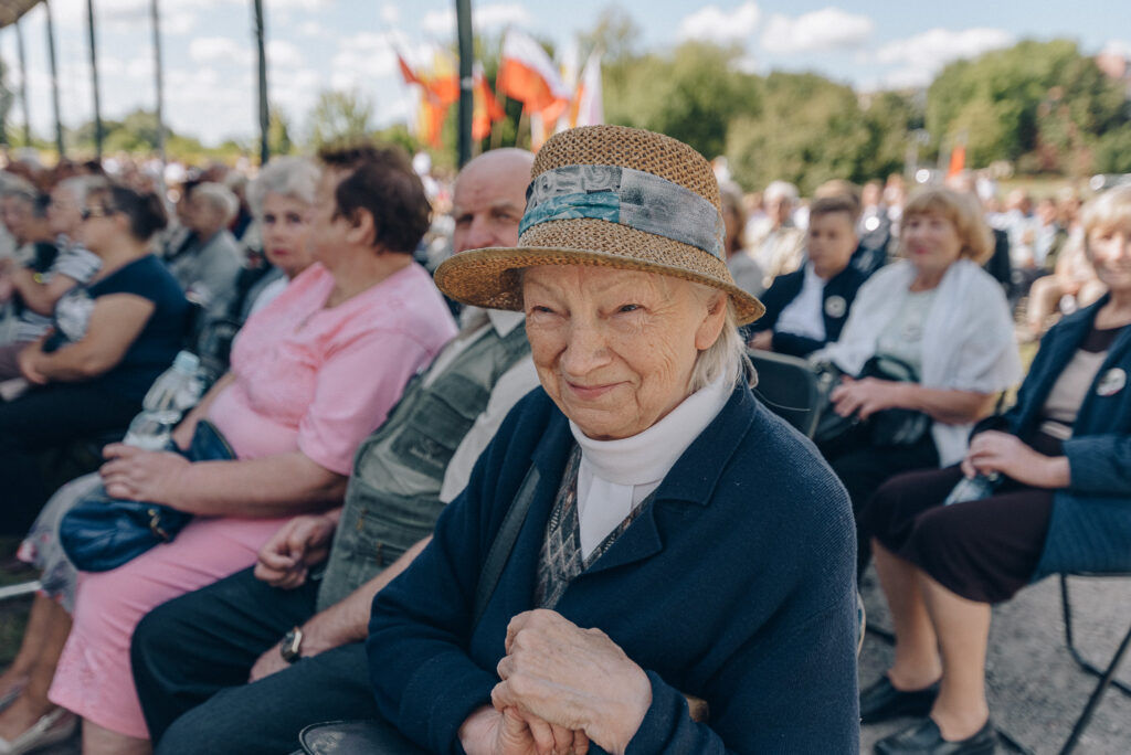 Zdjęcie przedstawia uśmiechniętą starszą Panią w kapeluszu.