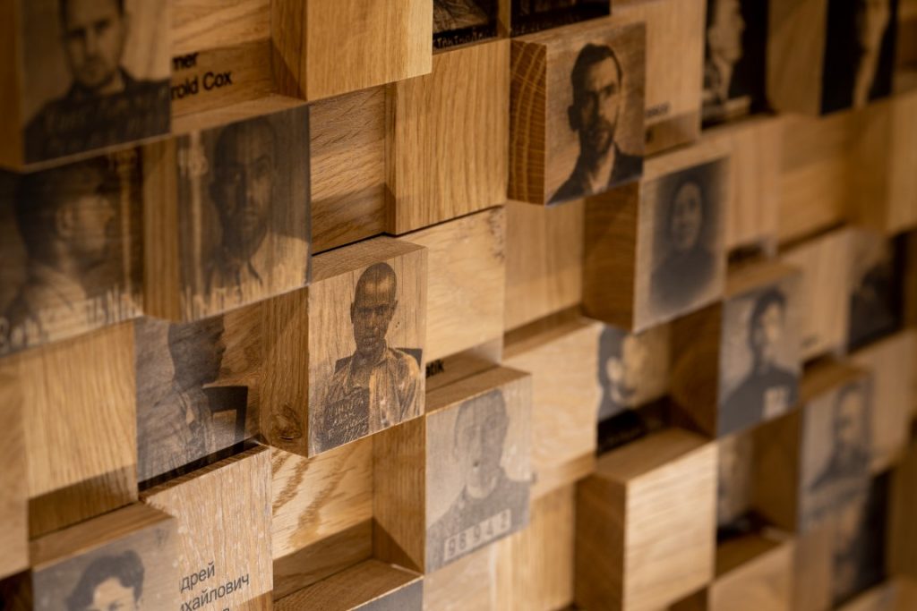Zdjęcie przedstawia portrety ludzi na drewnianym kolażu.