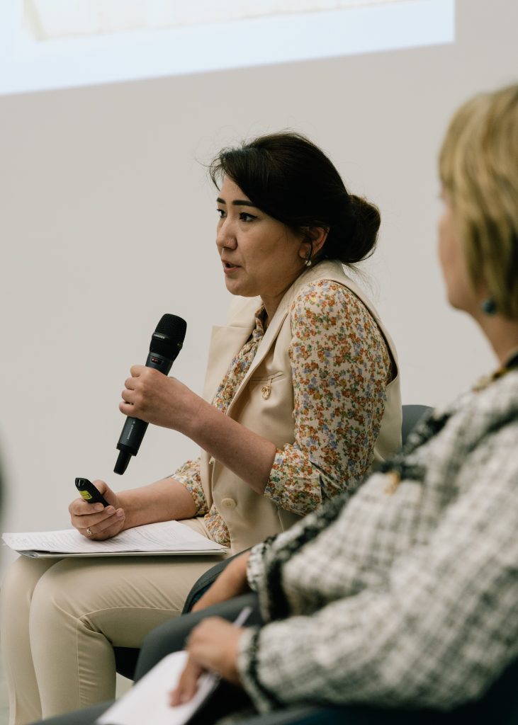 Zdjęcie przedstawia kobietę z mikrofonem na sali konferencyjnej