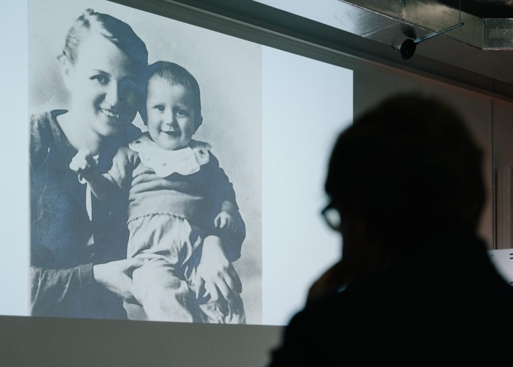 Zdjęcie przedstawia czarno biały portret  matki z dzieckiem wyświetlony podczas prezentacji na sali audiowizualnej.