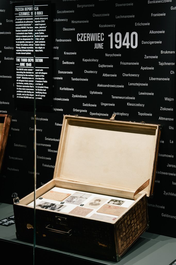 Zdjęcie przedstawia eksponat wystawy stałej. Jest to otwarta walizka ze zdjęciami.