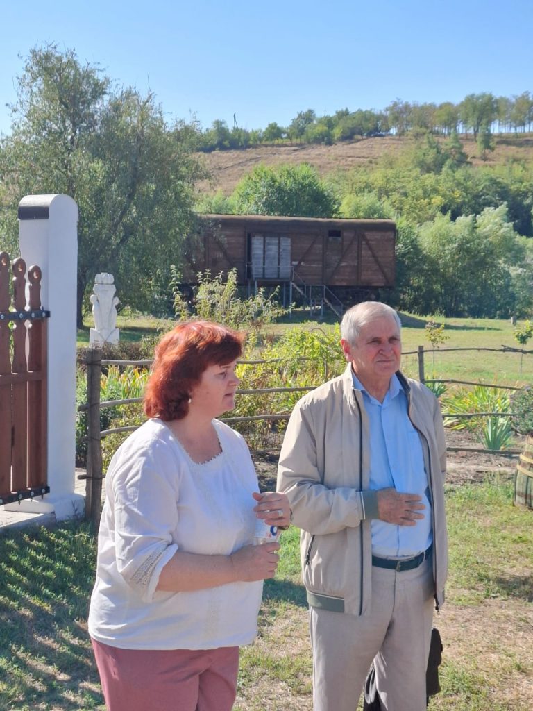 Kobieta i mężczyzna stoją obok siebie, w tle wagon - pomnik.