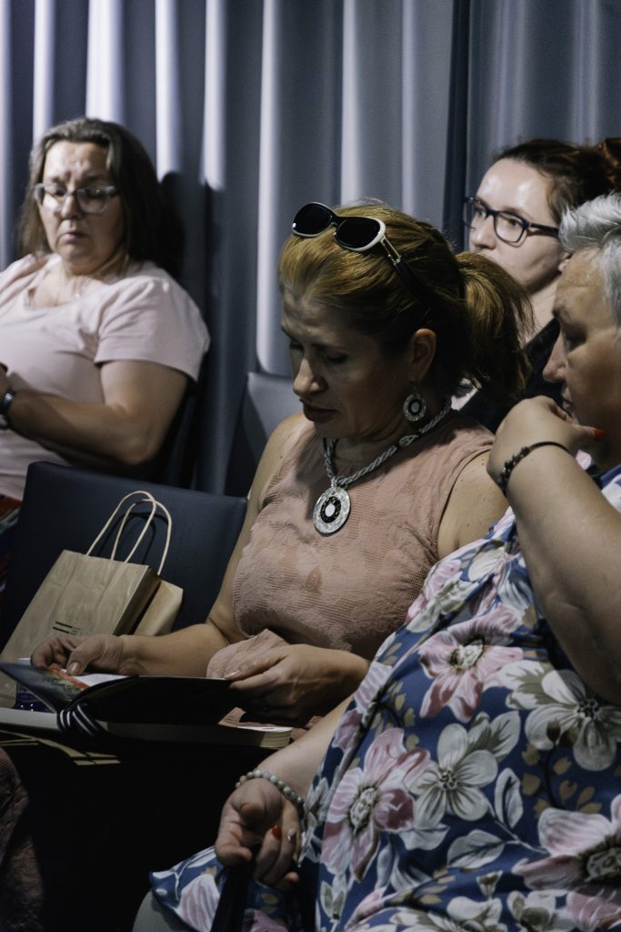 Grupa nauczycieli słucha wykładu. Na pierwszym planie kobieta przeglądająca książkę.