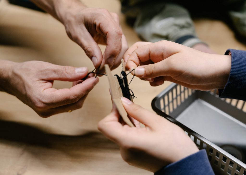 Widoczne są dwie pary rąk nad stołem. 