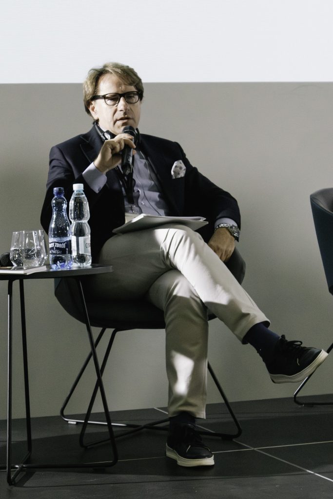 Dyrektor Muzeum Pamięci Sybiru prof. Wojciech Śleszyński siedząc na fotelu przemawia do mikrofonu.