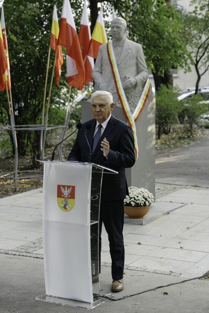 Prezydent Tadeusz Truskolaski stojąc przy mównicy przemawia podczas uroczystości odsłonięcia pomnika Seweryna Nowakowskiego. W tle pomnik oraz flagi.