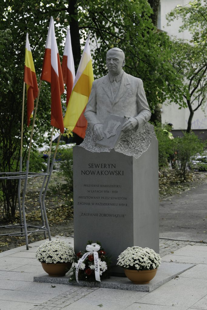 Pomnik Seweryna Nowakowskiego. W tle flagi Polski