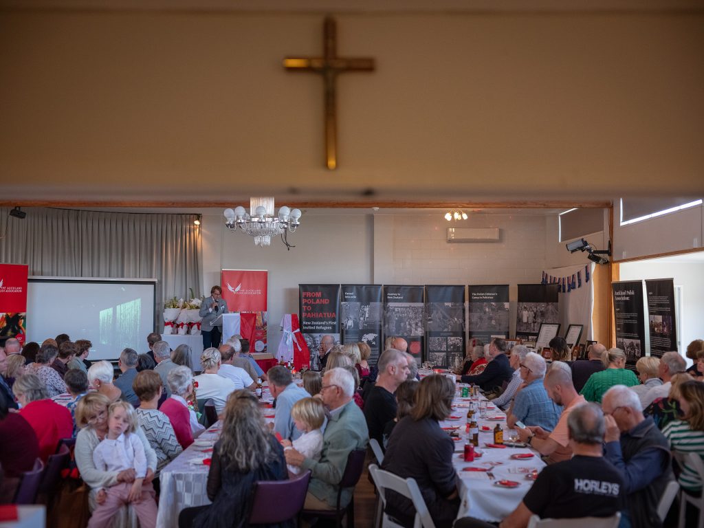 W dużej sali kilkadziesiąt osób siedzi przy stołach. W głębi przy mównicy widać prof. Wojciecha Śleszyńskiego podczas przemówienia.