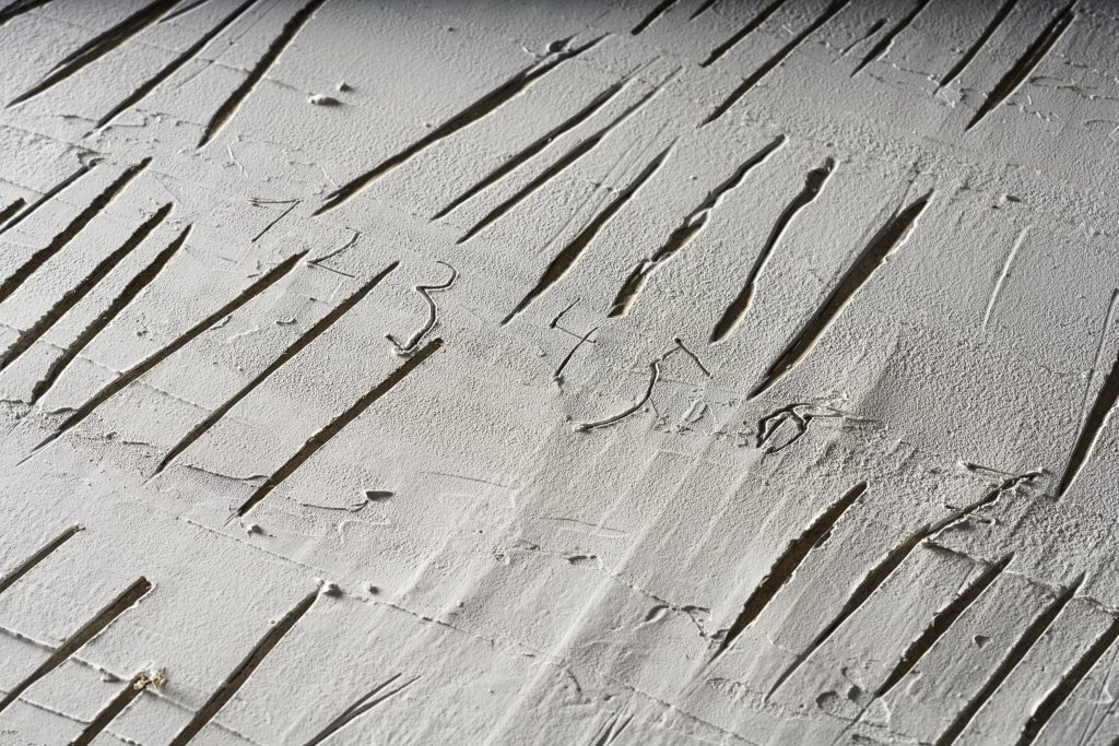 Fragment wystawy czasowej. W betonie jest wyżłobionych wiele pionowych kresek. Obok kresek są cyfry: 1, 2, 3, 4, 5, 6, 7.