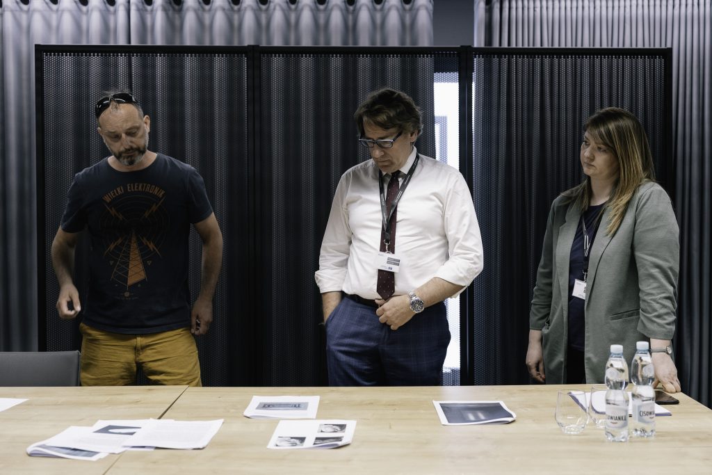 Prof. Wojciech Śleszyński stoi przy stole podczas prac nad nową wystawą czasową. Towarzyszą mu dwie osoby - dr Kamil Kopania, oraz kurator merytoryczny wystawy – Ewelina Kamieńska.