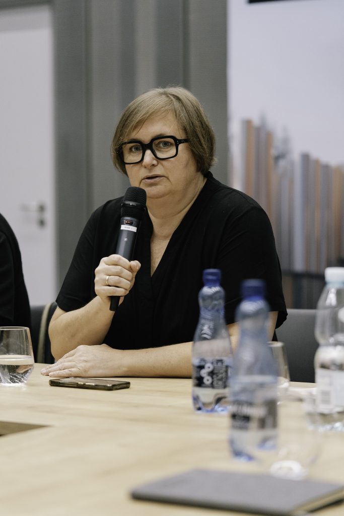 Kobieta przemawiająca przy stole.