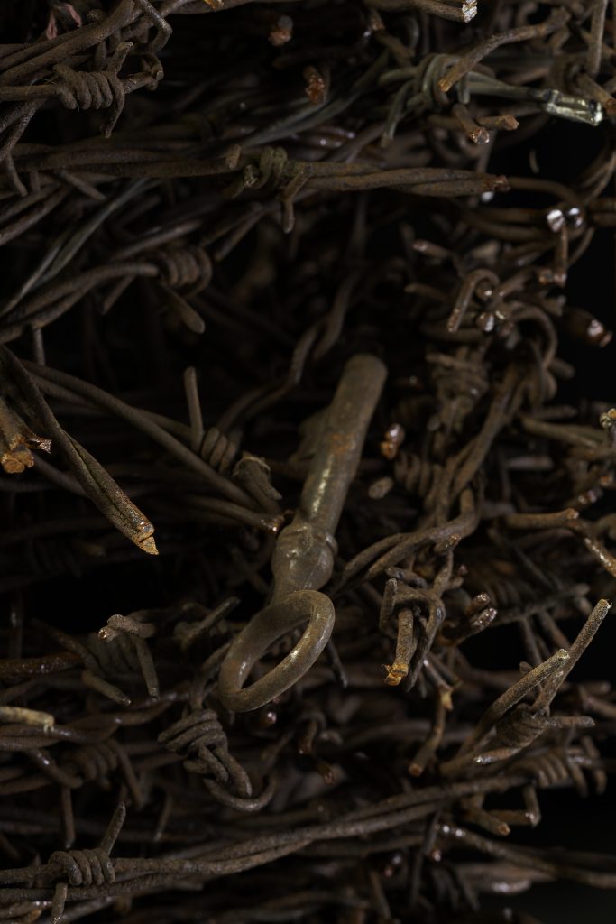 Wśród zwojów zardzewiałego drutu kolczastego leży klucz.