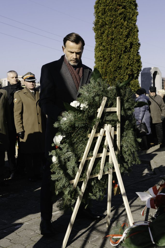 Jacek Brzozowski, wojewoda podlaski składa wieniec pod pomnikiem. W tle inni uczestnicy wydarzenia.