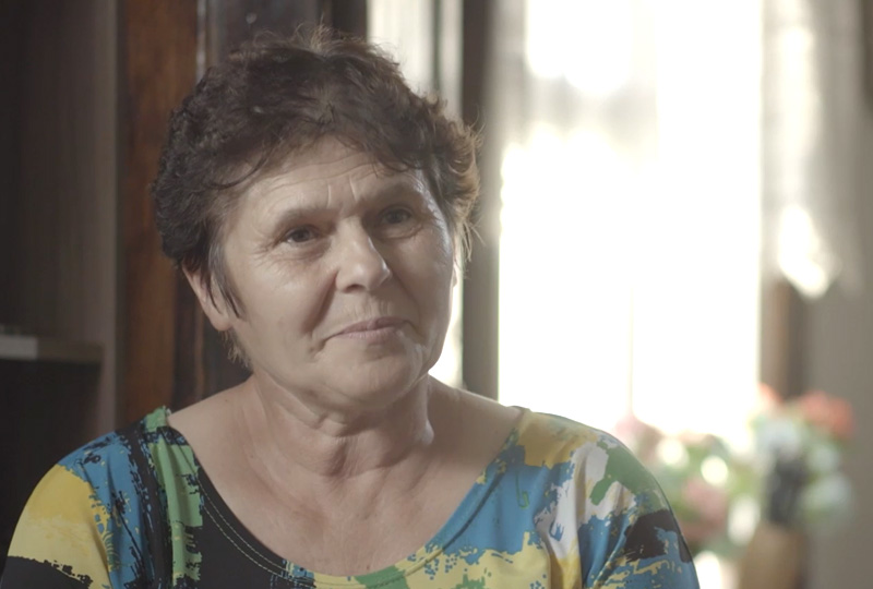 Galina Murawiecka, starsza osoba podczas udzielania wywiadu. W tle widać jasno oświetlone okno promieniami słońca.