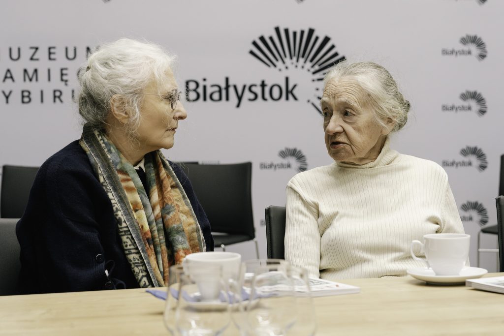 Dwie starsze uczestniczki posiedzenia Komisji Syberyjskiej siedzą przy stole. Rozmawiają ze sobą.