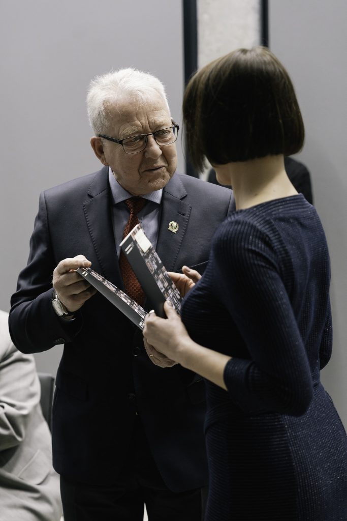 Dr Sylwia Szarejko rozmawia z jednym z uczestników wydarzenia. Jest to starszy mężczyzna w garniturze.