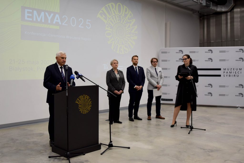 Konferencja prasowa EMYA 2025 w Białymstoku: przy mównicy stoi Prezydent Białegostoku Tadeusz Truskolaski przemawiający. W tle stoją inni uczestnicy wydarzenia.