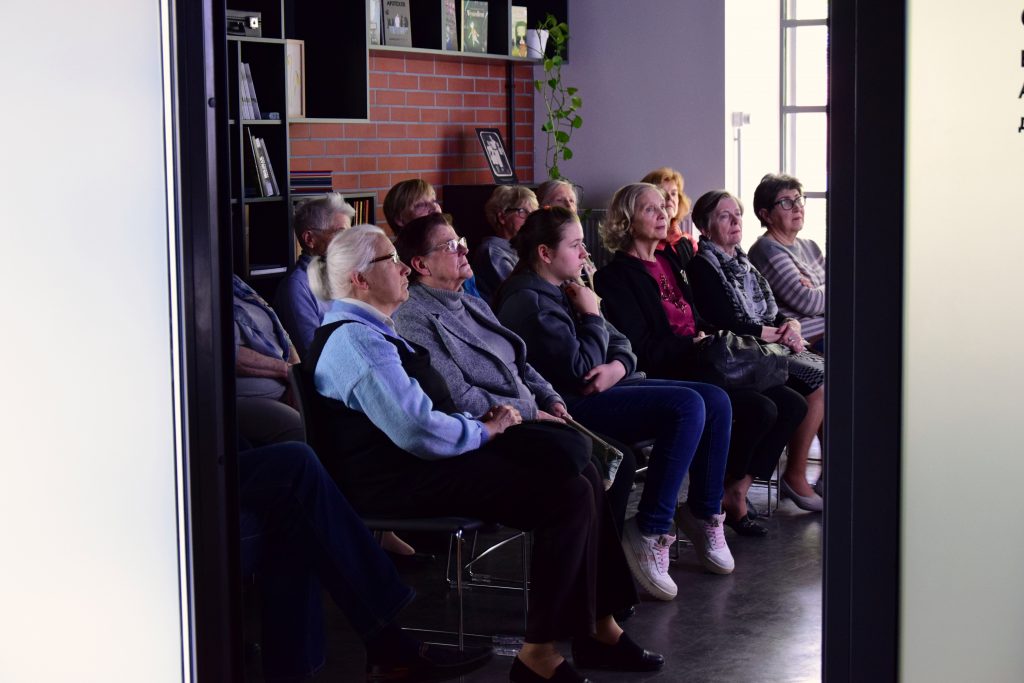 Grupa ludzi słucha prezentacji poświęconej zwierzętom na Syberii. 